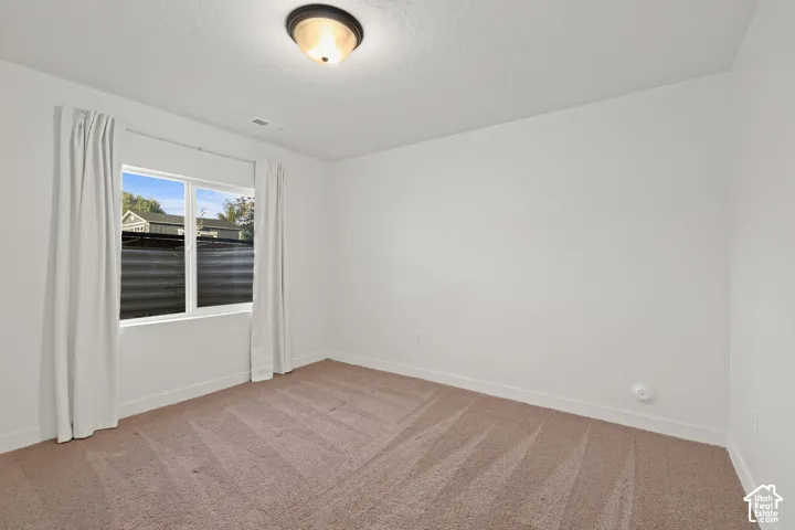 Neutral-toned carpeted flooring, white walls, and a recessed ceiling light fixture with a singular window featuring a dual-pane frame