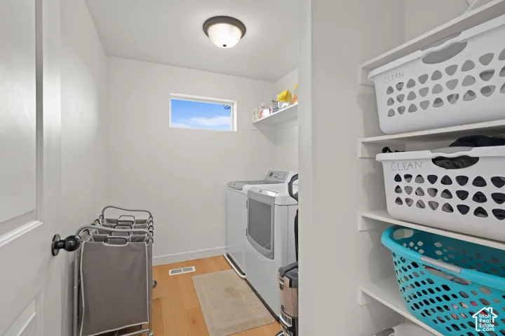 Utility room featuring wood-finish flooring, a rectangular window, overhead dome lighting, and built-in white shelving
