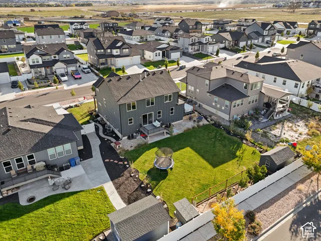 Two-story residence with vertical siding, elevated rear deck, fenced backyard, manicured lawn, and detached storage structure