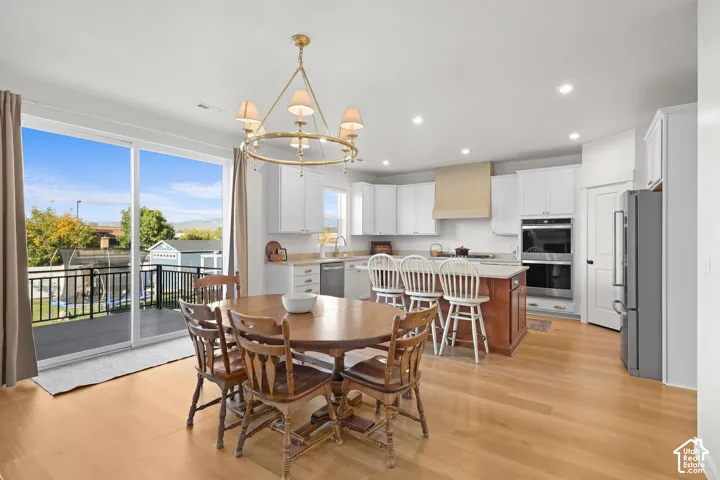 Kitchen featuring a center island, wood-finish flooring, custom range hood, recessed lighting, and stainless steel double wall ovens