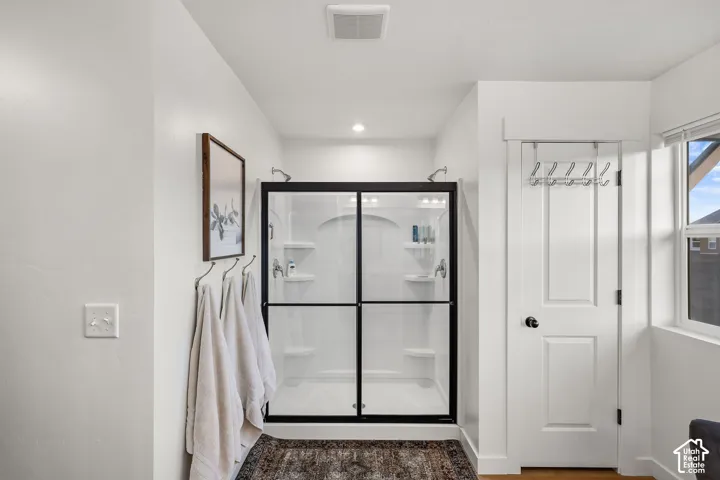Walk-in shower featuring a white surround, integrated shelving, and a matte black frame, complemented by a white two-panel interior door with matte black hardware
