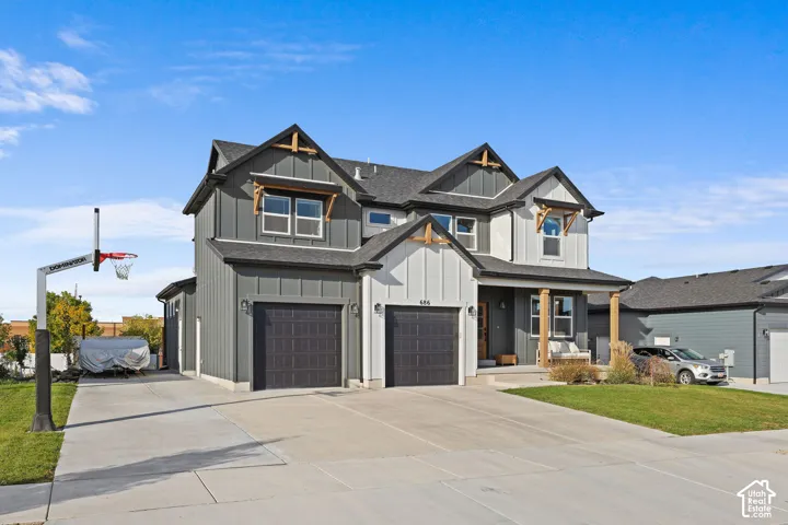 Multi-level residence featuring board-and-batten siding, decorative wood gable brackets, a covered front porch, and a two-car garage