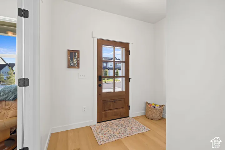 Entryway featuring a wood-finish entry door with glass pane detailing, neutral wall tones, and wood-finish flooring