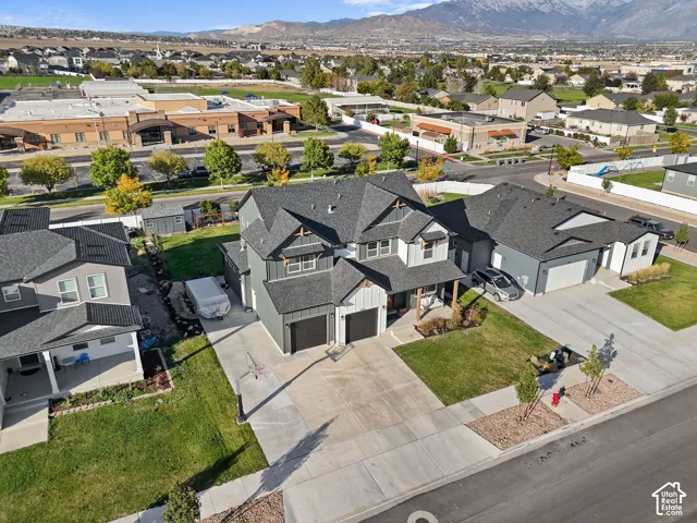 Multi-level residence featuring a dark-toned vertical siding facade, shingled roofing, an attached three-car garage, concrete driveway, and mountain backdrop