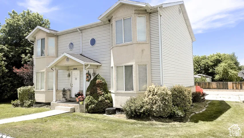 Two-story exterior featuring light-toned horizontal siding, dual bay windows, circular accent windows, and a covered front entryway