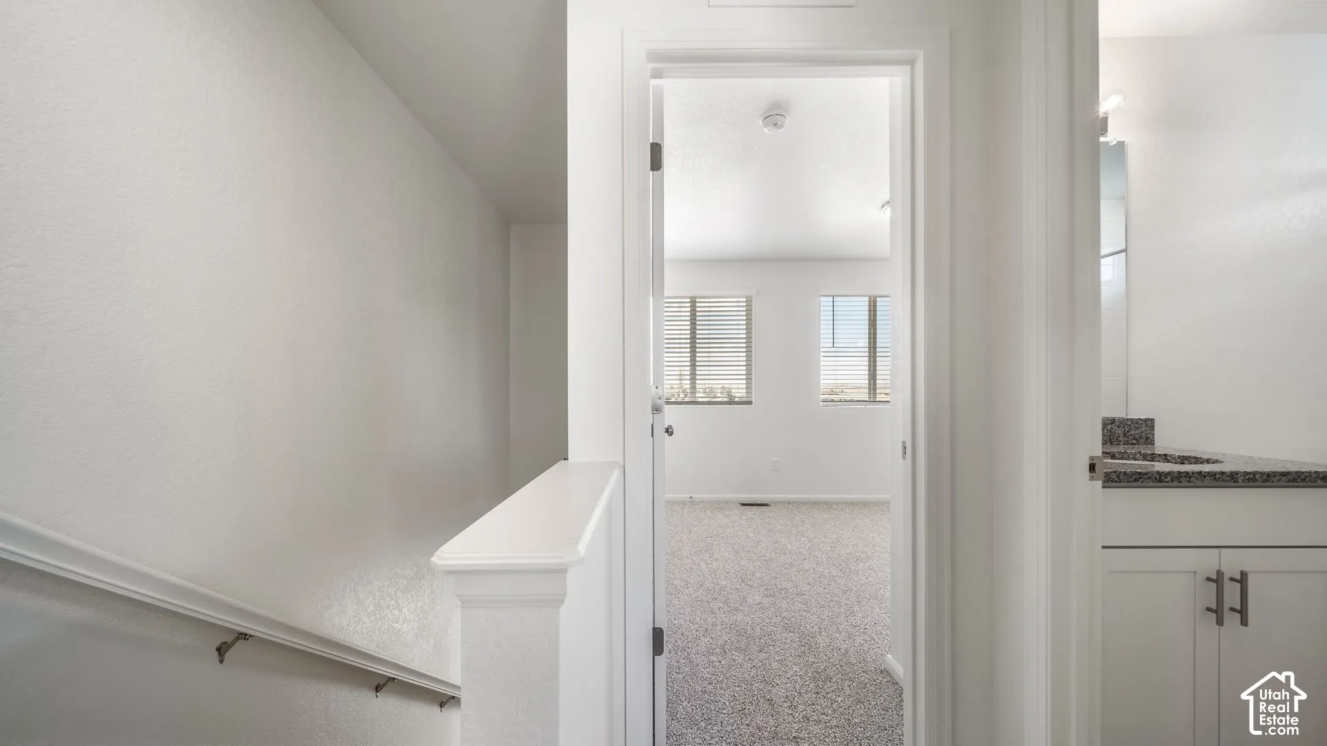 White cabinetry with stone-finish countertop, dual-pane windows, and neutral carpeting
