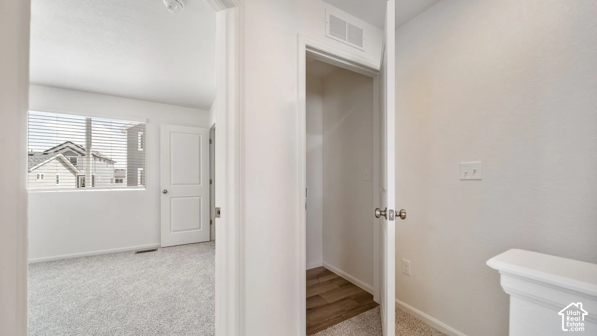 Interior space featuring neutral wall tones, carpeted flooring, two-panel interior doors, and a reach-in closet with wood-finish flooring
