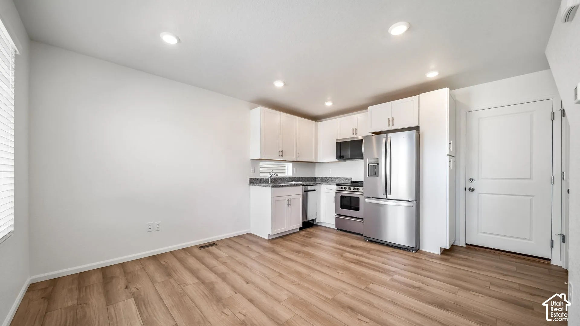 Kitchen featuring white cabinetry, stone-finish countertops, stainless steel appliances, recessed lighting, and wood-finish flooring