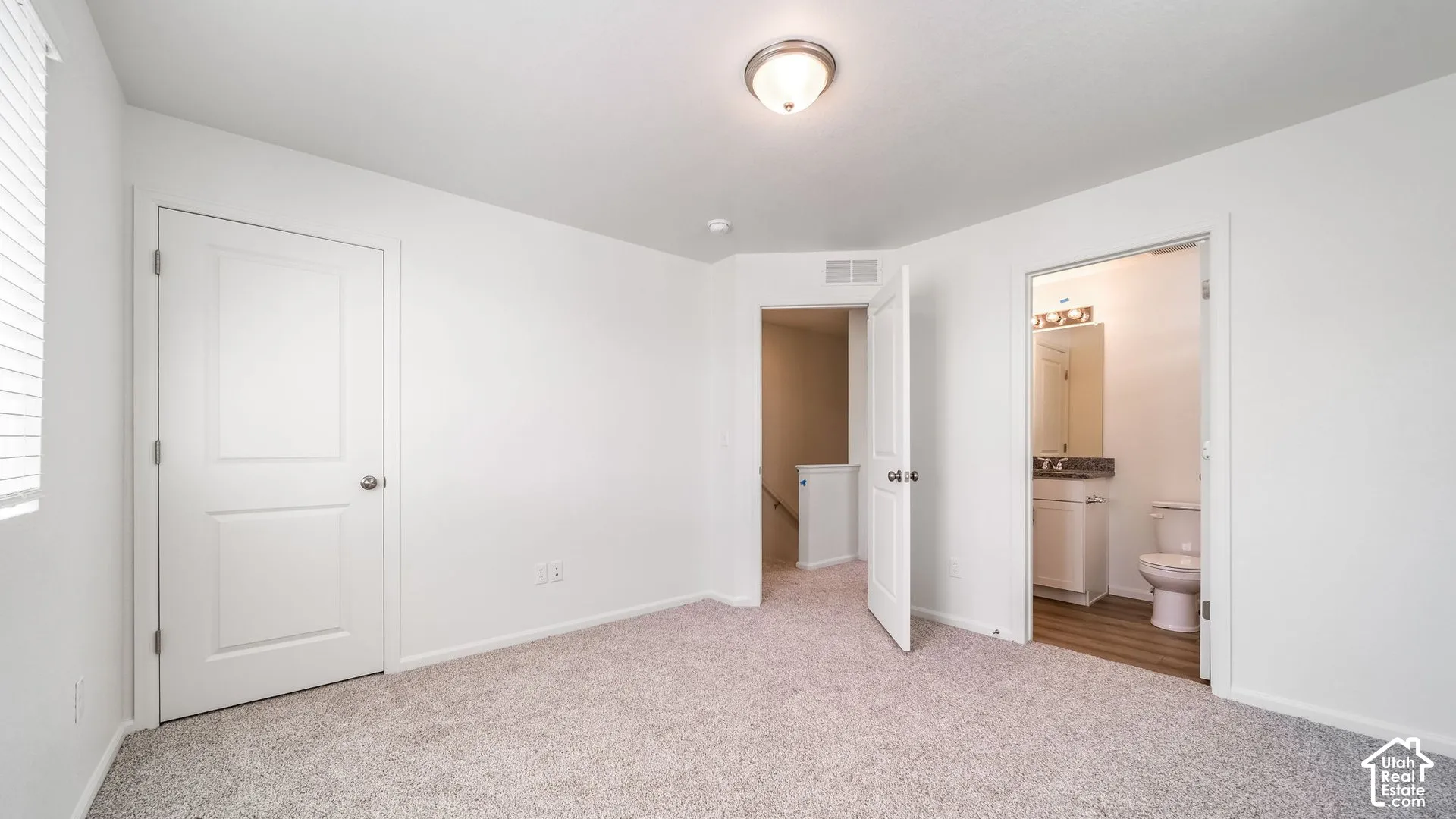 Interior room featuring neutral-toned carpeting, white walls, flush-mount ceiling lighting, and solid-core paneled doors