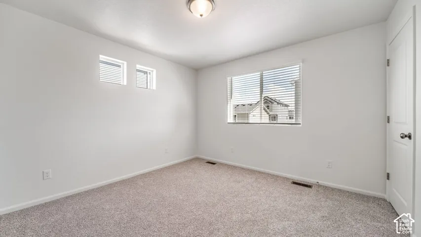 Neutral-toned wall-to-wall carpeting, high-reaching windows for natural illumination, overhead flush-mount lighting, and solid-core interior door with metallic hardware