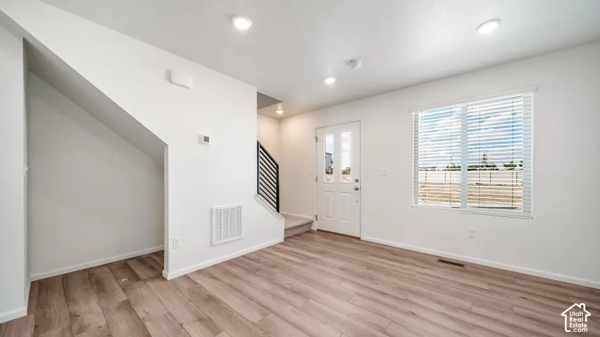 Interior space featuring wood-finish flooring, recessed lighting, a multi-pane entry door, and a built-in recessed wall alcove