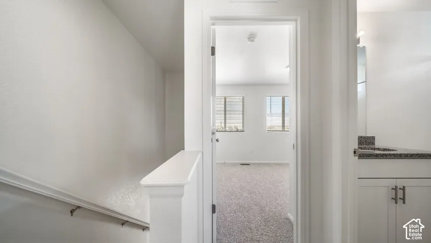 White cabinetry with stone-finish countertop, dual-pane windows, and neutral carpeting