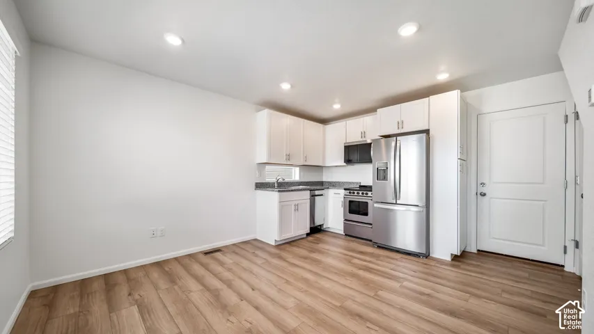 Kitchen featuring white cabinetry, stone-finish countertops, stainless steel appliances, recessed lighting, and wood-finish flooring