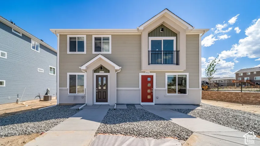 Two-story exterior featuring dual entryways, lap siding, a metal balcony railing, and concrete pathways