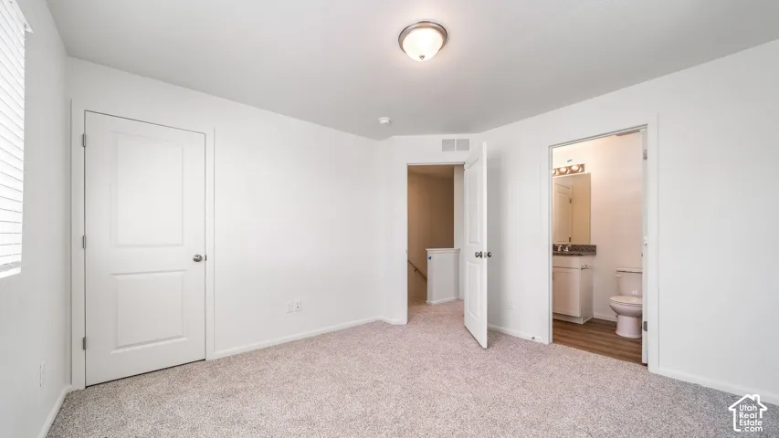 Interior room featuring neutral-toned carpeting, white walls, flush-mount ceiling lighting, and solid-core paneled doors