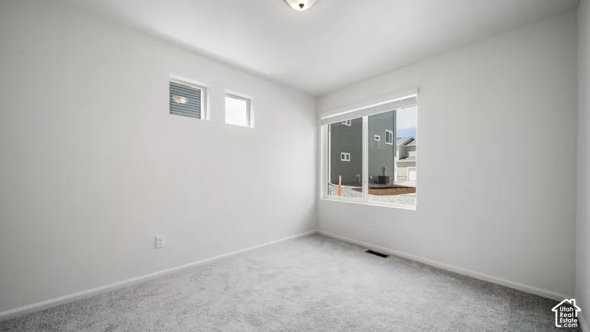 Neutral-toned interior space featuring wall-to-wall carpeting, high-placed windows, and a large multi-pane window
