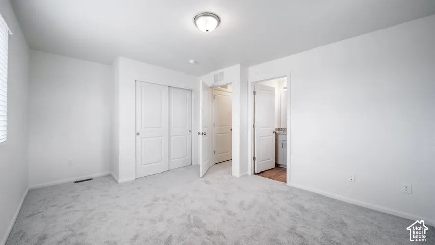 Neutral-toned carpeting, sliding closet doors, flush-mount ceiling lighting, and solid-core panel doors