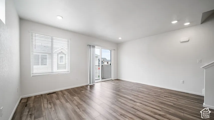 Interior space featuring wood-finish flooring, recessed lighting, neutral wall paint, and a sliding glass door providing external access