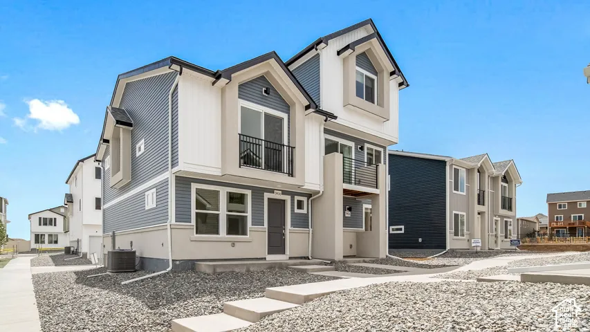 Multi-level exterior featuring horizontal and vertical siding, dual upper-level balconies with metal railings, and concrete entry steps