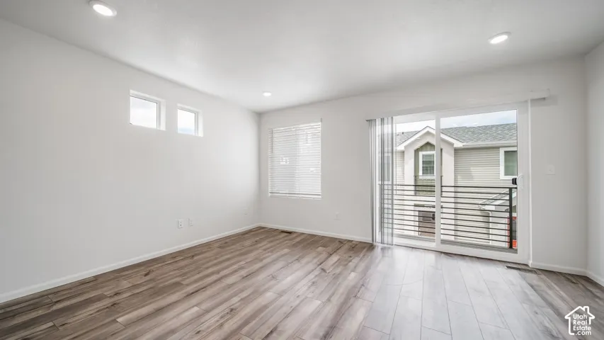 Interior space featuring wood-finish flooring, recessed lighting, clerestory windows, and sliding glass door with access to a railed balcony