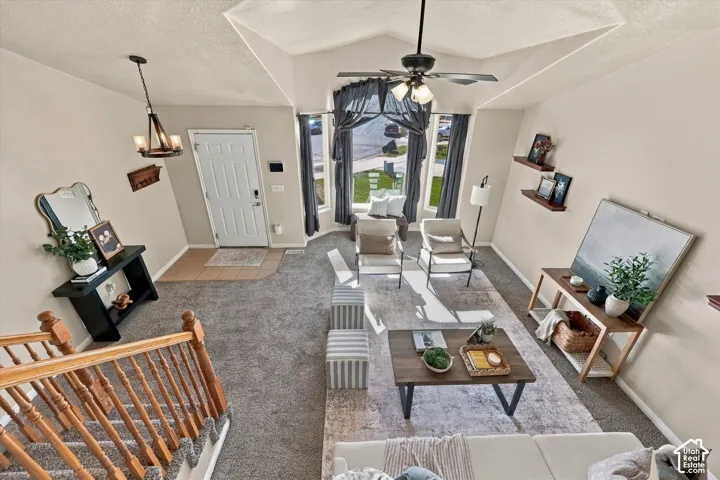 Vaulted ceilings, a prominent bay window, and a wooden stair railing featuring carved balusters