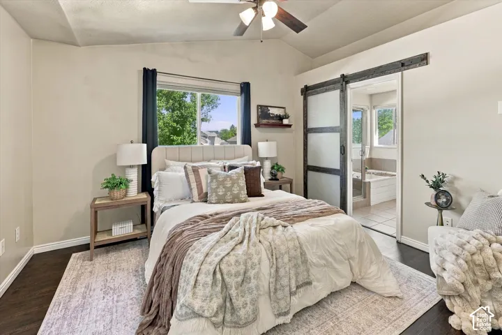 Vaulted ceilings with a ceiling fan, dark wood-finish flooring, and a sliding barn door with frosted glass panels