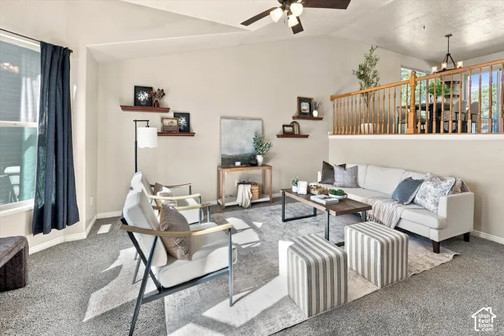 Vaulted ceilings, built-in wooden wall shelving, ceiling fan with light fixture, and wood-railed overlook