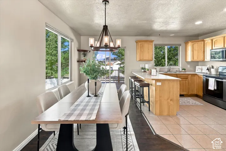 Kitchen and dining area featuring natural wood cabinetry, a wrap-around breakfast bar, ceramic tile flooring, and a multi-arm metal chandelier