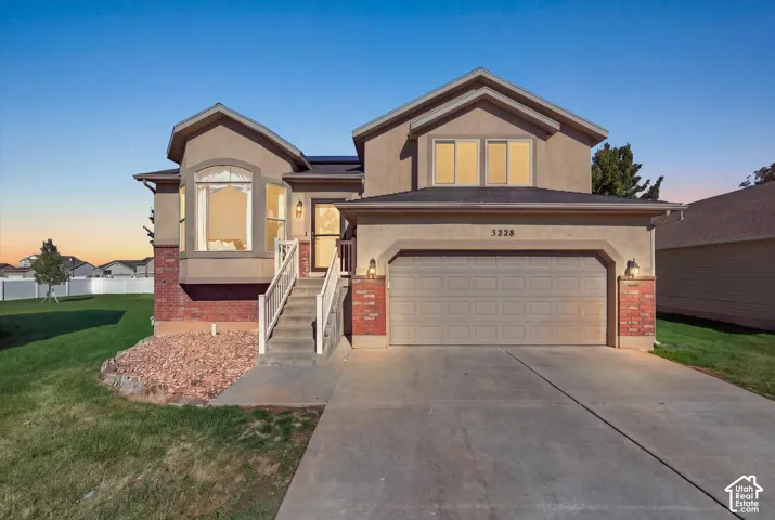 Two-story exterior featuring a brick and stucco facade, an attached two-car garage, a bay window, and a concrete driveway