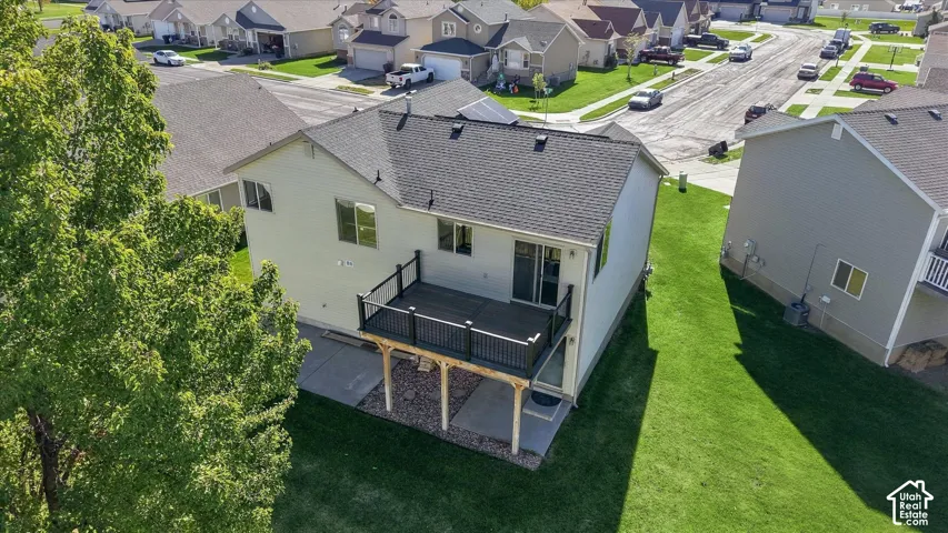 Elevated deck with black railings, concrete patio, and fenced-in lawn area