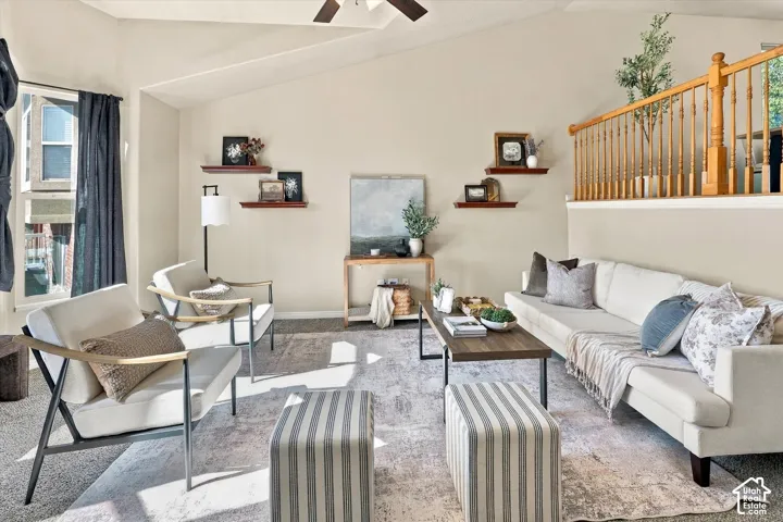 Living area featuring a vaulted ceiling, wood-finish railing with vertical balusters, and wall-mounted shelving
