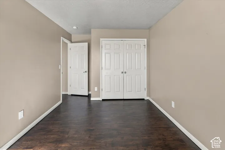 Room with dark wood-finish flooring, neutral wall tones, white six-panel interior doors, and dual-door closet storage