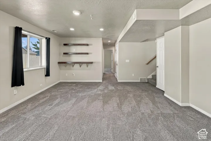 Interior space featuring wall-to-wall carpeting, recessed ceiling lighting, and three custom wood-finish floating shelves