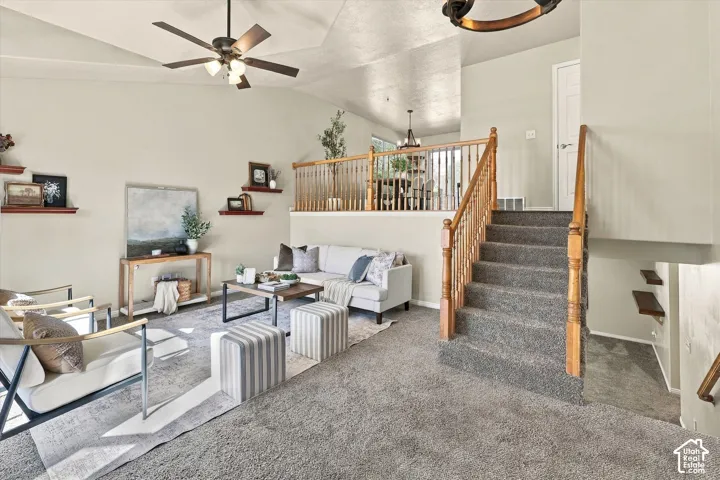 Vaulted ceilings, carpeted flooring, wood-finish railing, integrated wall shelving, and overhead ceiling fan