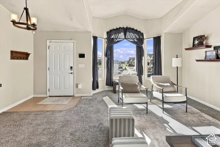 Vaulted ceilings, bay window, tile entryway, and overhead chandelier