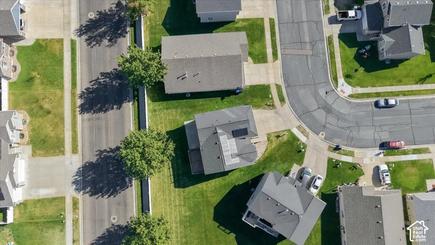 Aerial perspective featuring a residential lot with a concrete driveway and solar panel array mounted on the roof