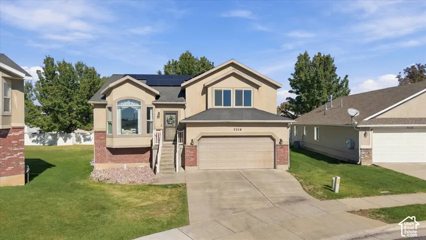 Two-story residence featuring a stucco and brick exterior, asphalt shingle roof, roof-mounted solar panels, and an attached two-car garage