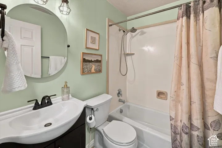 Bathroom featuring a dark wood-finish vanity, circular wall-mounted mirror, dual-handle faucet, and a tub-shower combination with an adjustable-height handheld shower head