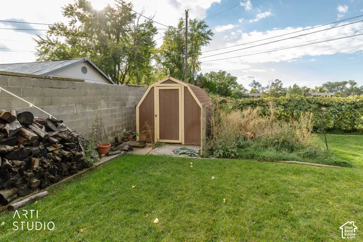 Backyard storage shed with a gambrel roof, concrete block perimeter wall, and manicured lawn