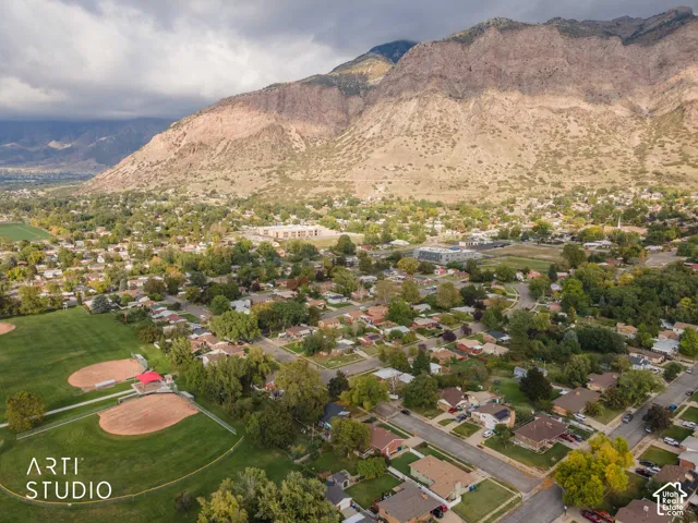 Aerial perspective featuring mountain terrain, mature deciduous trees, and open green space