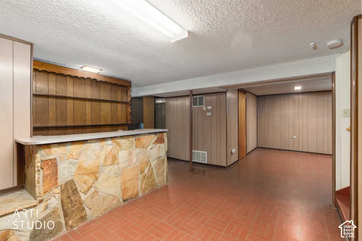 Custom built-in bar featuring natural stone masonry, integrated wood shelving, tile flooring, and wood-paneled walls
