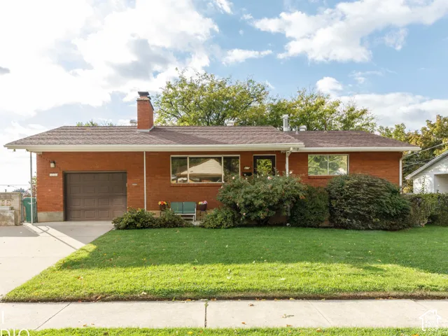 Brick exterior facade featuring a shingled roof, an attached single-car garage, an exterior brick chimney, and a concrete driveway