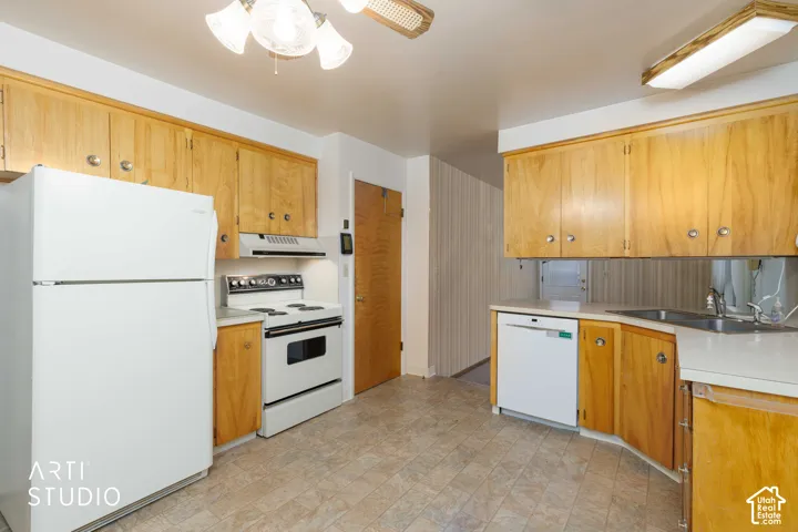 Kitchen featuring wood cabinetry, white appliances, a stainless steel sink with a mounted faucet, and tile flooring