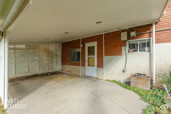 Covered carport featuring a concrete floor, brick exterior masonry, lattice privacy screening, and recessed lighting