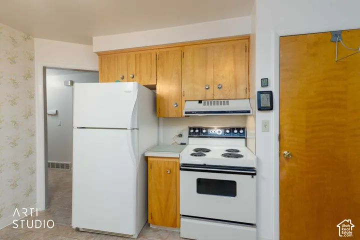 Kitchen featuring light-finish wood cabinetry, white appliance suite, electric range, and integrated range hood