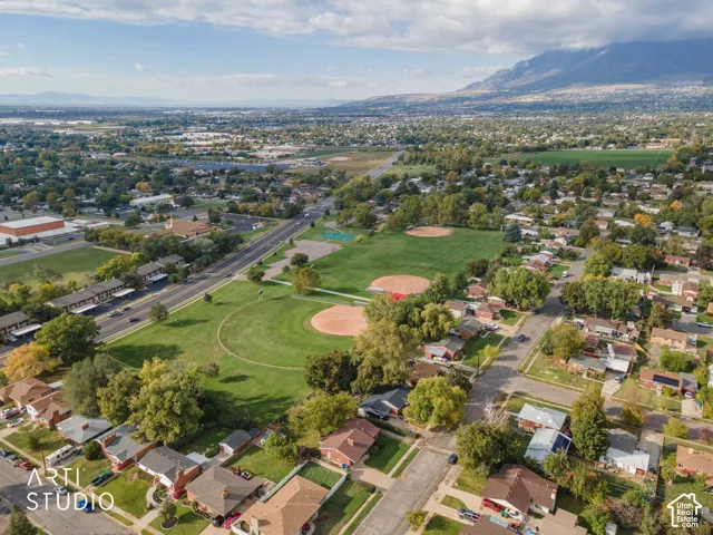 Aerial perspective showcasing expansive green space, baseball diamonds, mature trees, and a mountain range backdrop