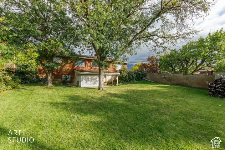 Expansive backyard featuring mature shade trees, a grass lawn, and a perimeter masonry wall
