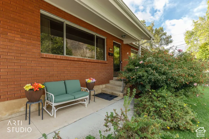 Red brick exterior featuring a concrete porch, wide rectangular window, and mature shrubbery
