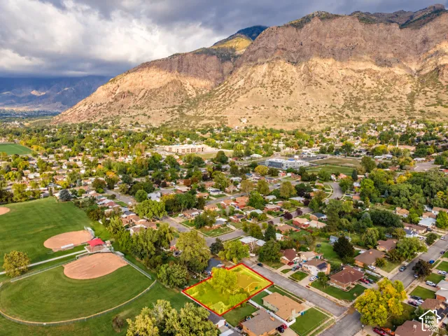 Property Lines are approximate. Buyer to verify all. Aerial perspective highlighting a parcel of land bordered by mature trees and a residential street, set against a prominent mountain backdrop