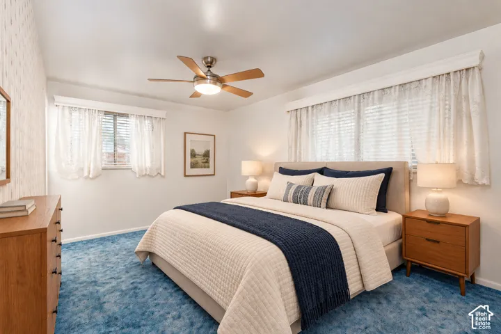 Room featuring patterned wallpaper, carpeting, a ceiling fan with integrated lighting, and windows with built-in valances
